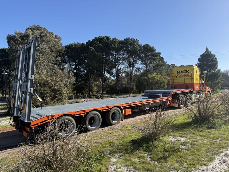 Mack prime mover and empty float trailer parked on a gravel verge