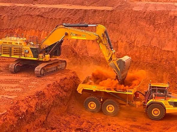 Excavator loading an articulated dump truck on a bulk earthworks cut
